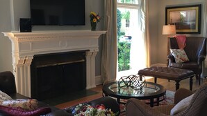 A living room with a fireplace, a television, a comfortable seating area with a sofa and chairs, and a view through a window. - Stunning, Large, Beautifully Decorated Home in Downtown Lodi with Spa Amenities  (Lodi)