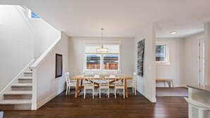 A spacious dining area with a wooden table and chairs, a staircase, and a view of the outdoors. - Hillside Haven - Bend's West Side, Work-from-Home Office, New, Modern, Light, Bright (Bend)