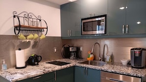 Une cuisine dotée d’un plan de travail en granit, d’appareils électroménagers en acier inoxydable et de meubles de couleur turquoise.