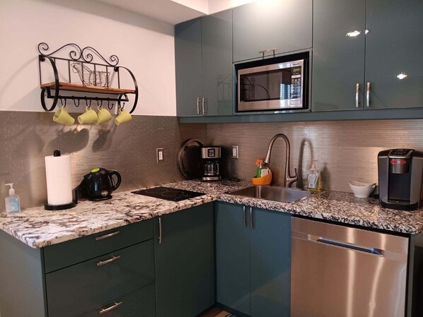 Una cocina con encimera de granito, electrodomésticos de acero inoxidable y armarios color turquesa.