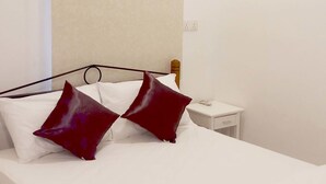 Una habitación de hotel con una cama, una mesita de noche y un aire acondicionado.