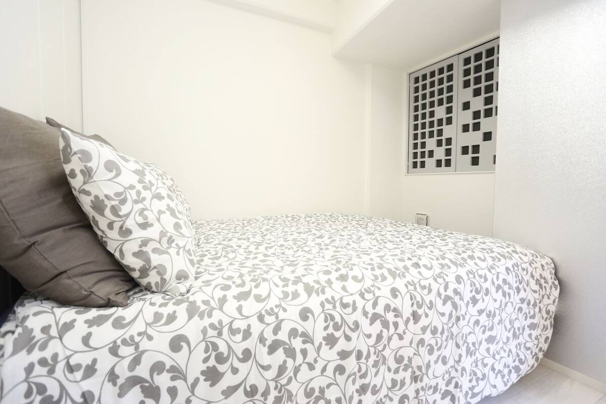 Une chambre à coucher avec un lit, un oreiller et une bouche d’aération fixée au mur.