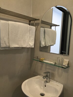 A bathroom with a white sink, a mirror, and a towel rack with two white towels. - Candyinn (Hue)