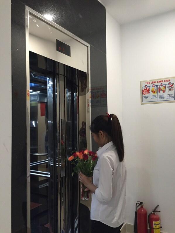 A person standing in front of an elevator with a fire extinguisher and a poster on the wall.