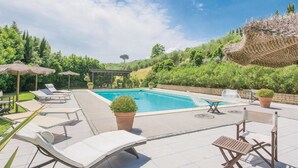 A swimming pool with lounge chairs and umbrellas, surrounded by greenery and a pergola. - Beautiful apartment in S.Rocco di Larciano PT with WiFi (S.Rocco di Larciano PT)