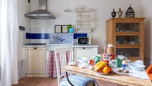 A kitchen with a gas stove, microwave, and a wooden cabinet with glass doors. - Beautiful apartment in S.Rocco di Larciano PT with WiFi (S.Rocco di Larciano PT)