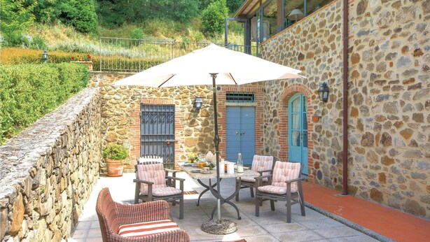 An outdoor patio with stone walls, a table with chairs, and a blue door. - Beautiful apartment in S.Rocco di Larciano PT with WiFi (S.Rocco di Larciano PT)