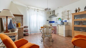 A cozy living room with a fireplace, orange chairs, and a dining area with a table and chairs. - Beautiful apartment in S.Rocco di Larciano PT with WiFi (S.Rocco di Larciano PT)