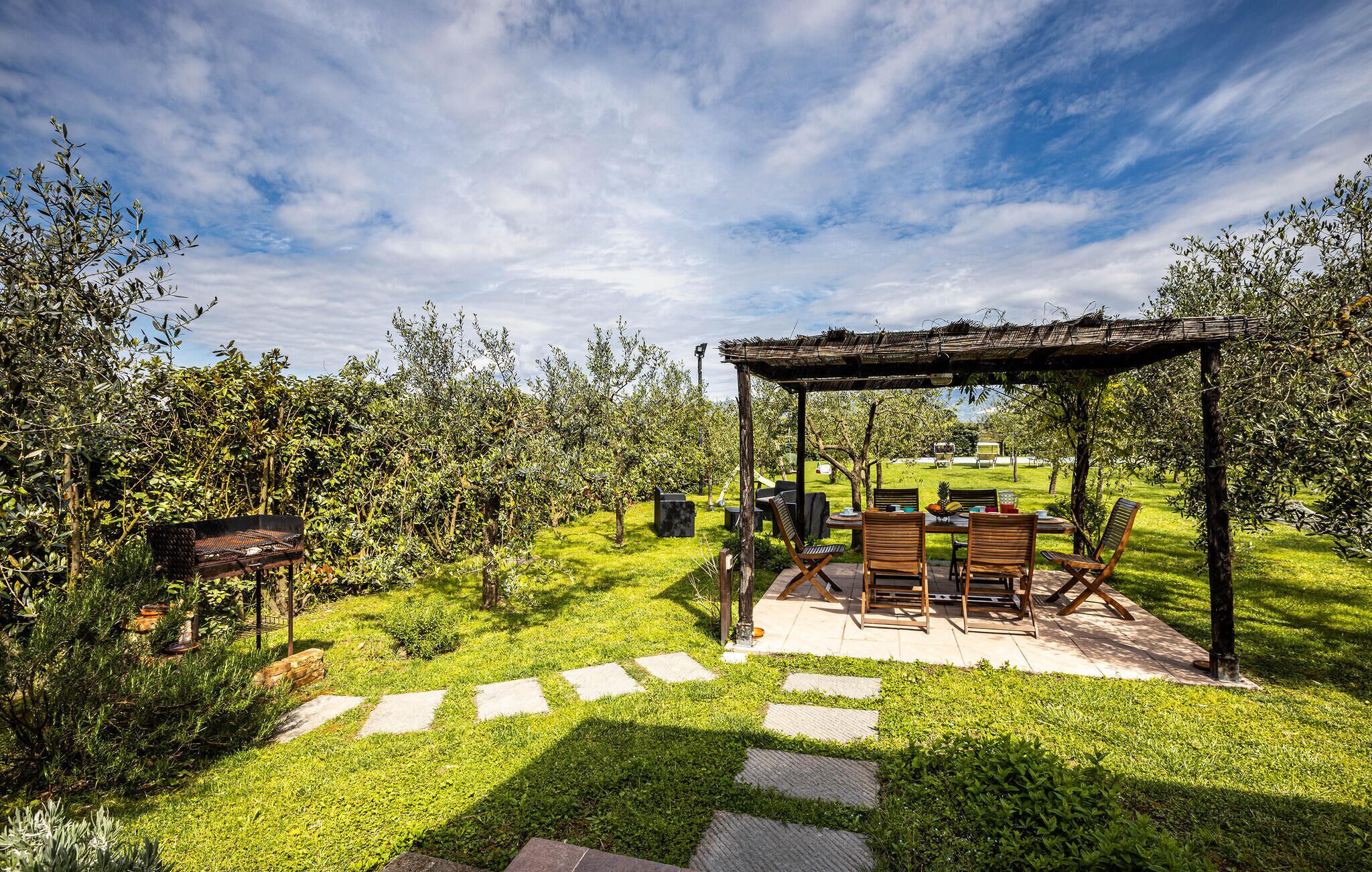 Un jardín con un pérgola, mobiliario exterior y un camino de piedra.