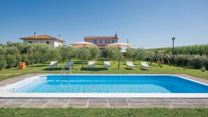 A swimming pool with lounge chairs and umbrellas, surrounded by a well-maintained lawn and a large house in the background. - Stunning home in Ponte Buggianese (Ponte Buggianese)