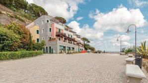 A multi-story building with a stone facade, balconies, and a paved courtyard. - 2 bedroom amazing apartment in Porto Azzurro (Porto Azzurro)