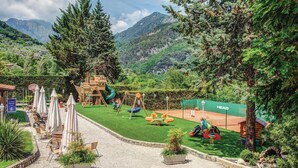 A playground with swings, slides, and climbing structures, surrounded by lush greenery and mountains in the background. - 2 bedroom pet friendly apartment in Tremosine -BS- (Tremosine -BS-)