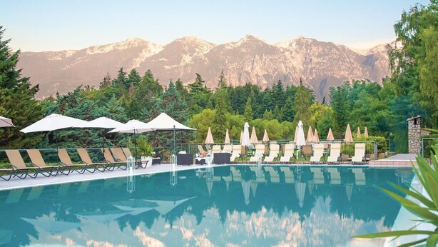 A pool with lounge chairs and umbrellas, surrounded by trees and mountains in the background. - 2 bedroom pet friendly apartment in Tremosine -BS- (Tremosine -BS-)