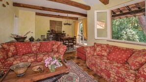 A cozy living room with floral-patterned sofas, a wooden coffee table, and a dining area with a table and chairs. - Stunning home in Castiglione d. Pescaia (Castiglione d. Pescaia)