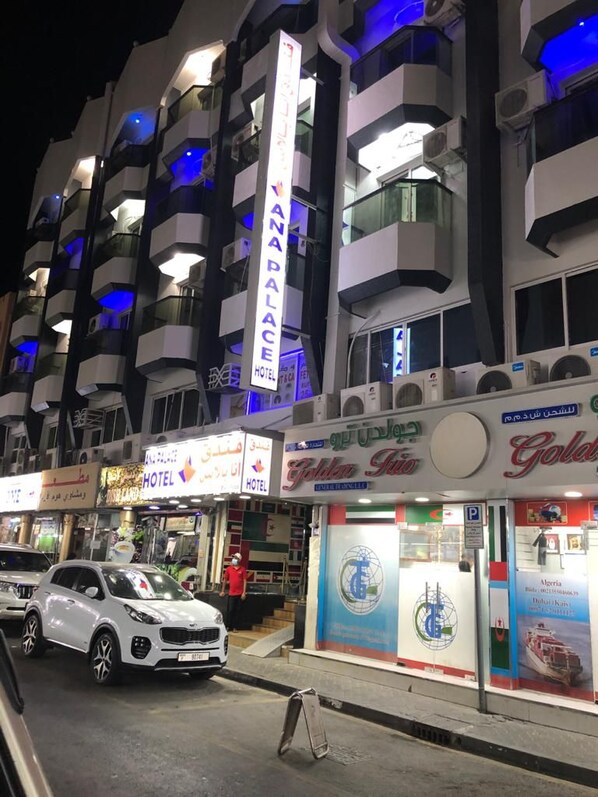 A hotel with multiple balconies, a prominent sign for 'Golden Trio Hotel,' and a visible car parked in front. - Ana Palace Hotel (Dubai)