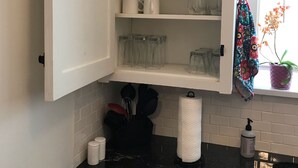 A kitchen with white cabinets, a black countertop, and a window with a potted plant. - Historic Phelps Mansion;  main level Suite #1  (Decorah)