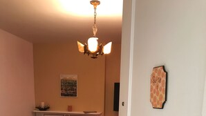 A living room with a fireplace, a sofa, a dining table, and a chandelier. - Historic Phelps Mansion;  main level Suite #1  (Decorah)