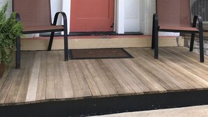 A porch with a red door marked "408", two wicker chairs, and a potted plant. - Historic Phelps Mansion;  main level Suite #1  (Decorah)