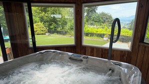 A hot tub with a view of a garden and mountains through large windows. - Cascades View A Frame (Snohomish)