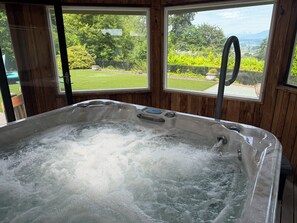 A hot tub with a view of a garden and mountains through large windows. - Cascades View A Frame (Snohomish)