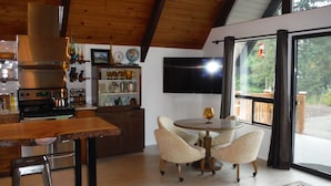 A modern kitchen with a wooden ceiling, a built-in stove, and a dining area with a round table and four chairs. - Cascades View A Frame (Snohomish)