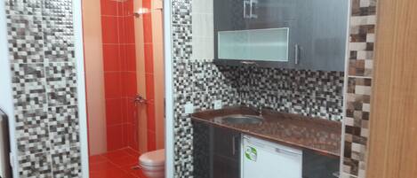 A bathroom with red and white tiled walls, a sink with a mirror above it, and a toilet.