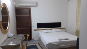 Ein Hotelzimmer mit Bett, Schreibtisch, Stuhl, Spiegel und Klimaanlage.