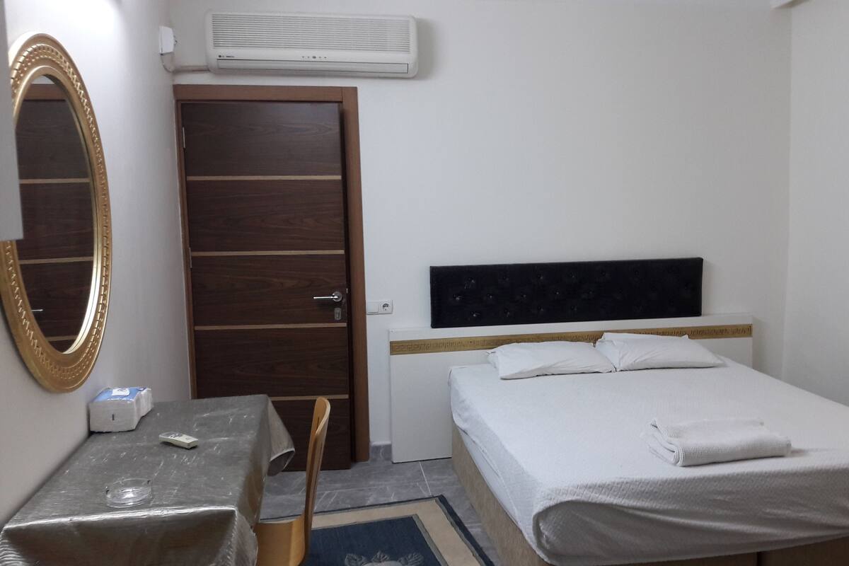 Ein Hotelzimmer mit Bett, Schreibtisch, Stuhl, Spiegel und Klimaanlage.
