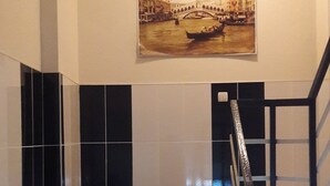 Eine Treppe mit schwarz-weißen Fliesen, einem Geländer und einem Bild einer Brücke über einem Fluss an der Wand.