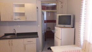 Eine kleine Küche mit Spüle, Schränken und einem Kühlschrank.