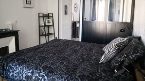 Un dormitorio con cama, escritorio, estante y puerta.