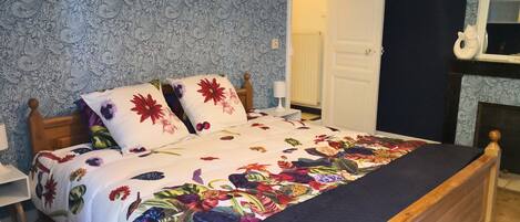 A bedroom with a floral bedspread, wooden headboard, and a nightstand with a lamp.