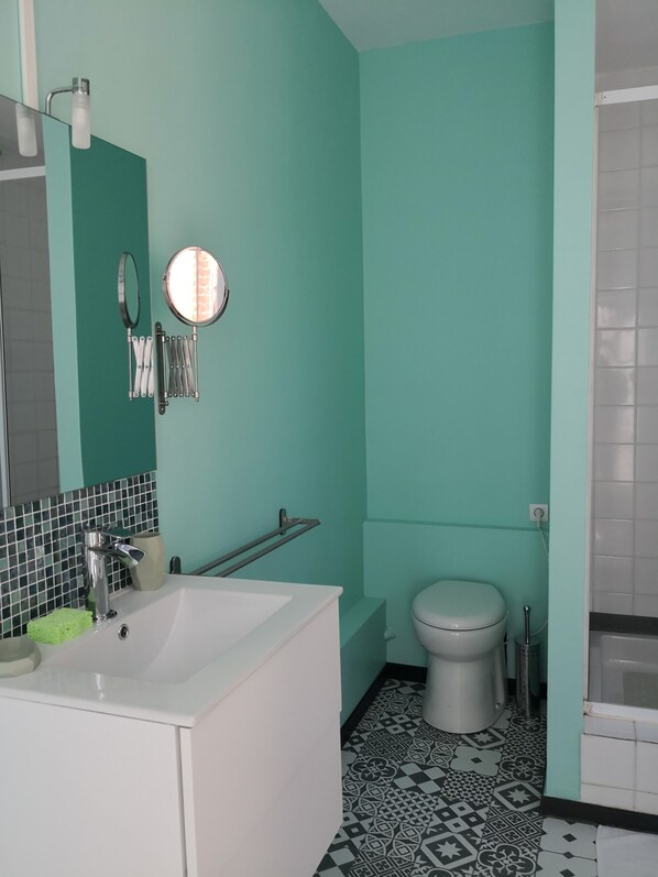 Un baño con un lavamanos blanco, un espejo, un inodoro y una bañera.