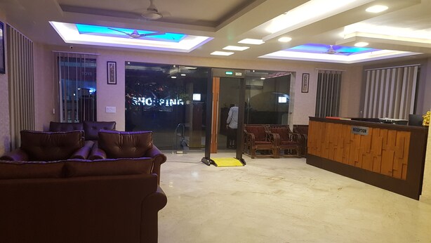 A lobby with a reception desk, a sofa, and a glass door leading outside. - Mira International (New Delhi)