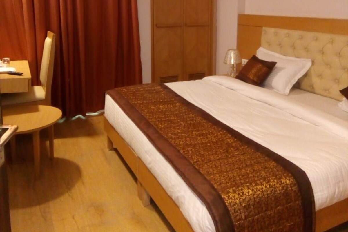 A hotel room with a wooden bed, a desk, a chair, and a wardrobe.