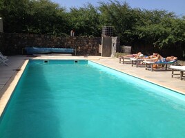 Una piscina al aire libre, sombrillas, tumbonas
