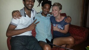 Three people sitting on a red couch in a room with plain walls. - Villa Vidura (Galle)