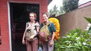 Two individuals standing at a doorway with backpacks, a water bottle, and flip-flops on the ground. - Villa Vidura (Galle)