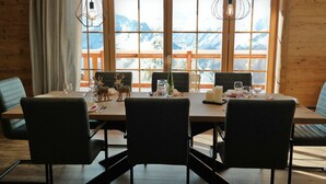A wooden dining table with four chairs, set for a meal with wine glasses and a candle. - Chalet d'exception**** with wellness area (Villard reculas)