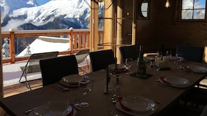 A dining area with a table set for four, overlooking a snowy mountain landscape. - Chalet d'exception**** with wellness area (Villard reculas)
