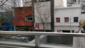 A multi-story building with a prominent red 'N' sign, a visible 'Banco Ciudad' sign, and a clear view of the street below. - Cute Abasto Apartment (Buenos Aires)