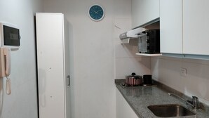 A compact kitchen with a built-in microwave, a stove, and a sink. - Cute Abasto Apartment (Buenos Aires)