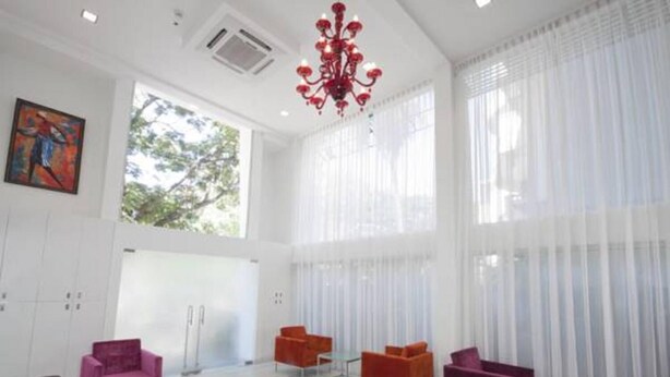 Una habitación amplia con ventanas grandes, una araña roja y muebles modernos.