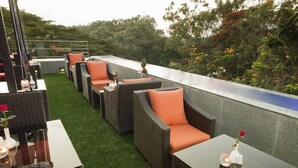 Terraza en la azotea con mobiliario de mimbre y barandilla de vidrio.