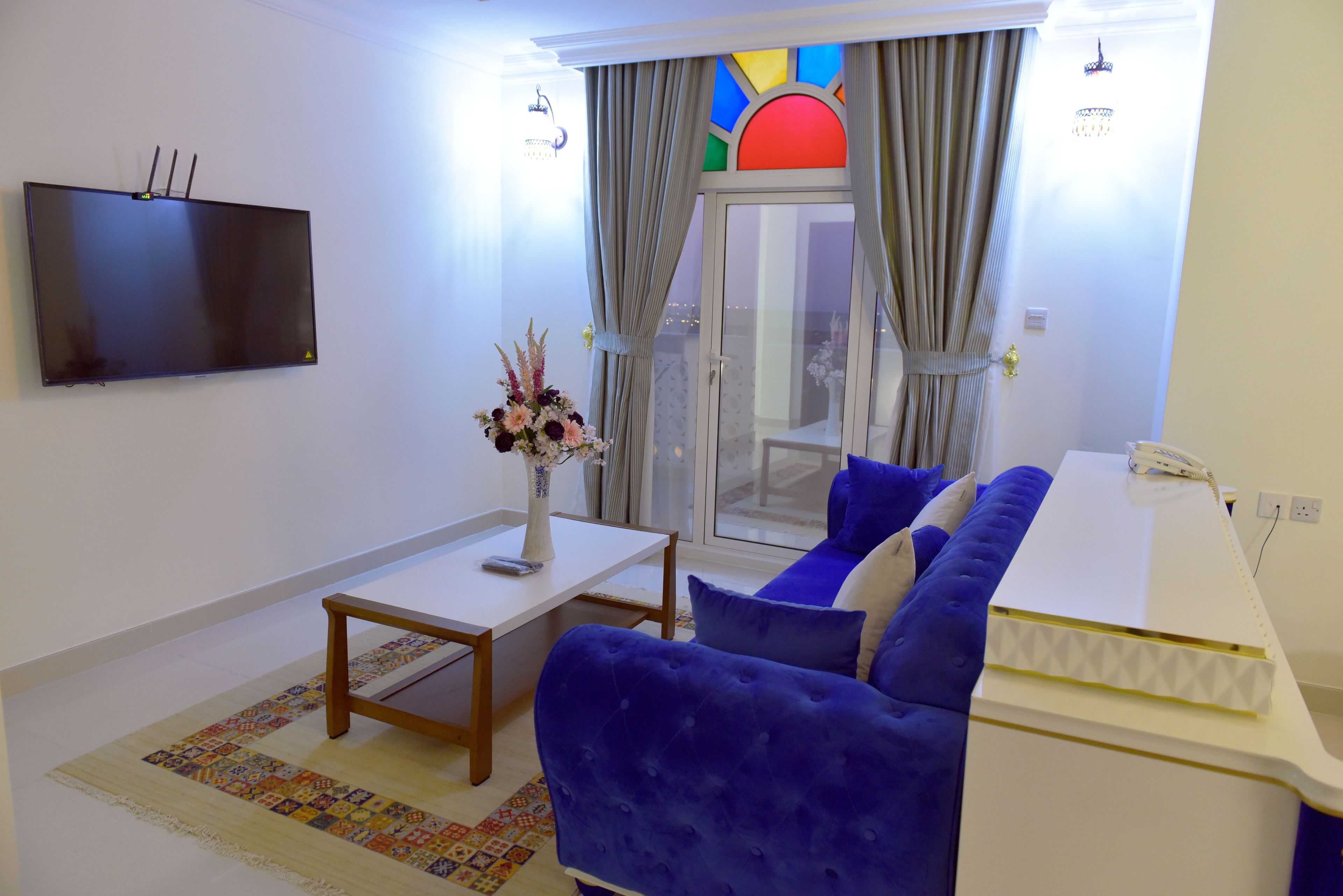 A living room with a flat-screen TV, a sofa, a coffee table, and a decorative vase.
