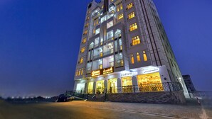 A multi-story hotel with illuminated signage for 'Shamar Hotel Apartment' and 'Coffee Shop'.