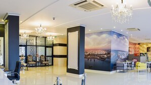 A hotel lobby with a large mural, chandeliers, and a reception area with seating.