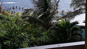 Un balcón con vista al océano y palmeras.