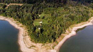 An aerial view of a forested area with a small cluster of buildings surrounded by water.
