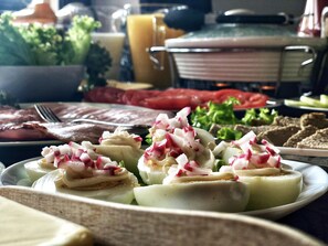 Una mesa de comedor con varios platos, incluyendo un plato con rábanos y queso en rodajas, y un vaso de jugo.